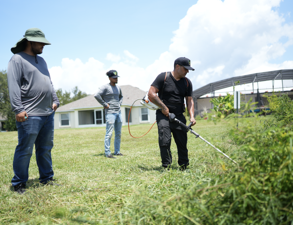 Landscaping expert leading a team in weed trimming.